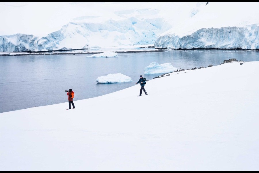 Expedition passengers walking beside an Antarctic Peninsula glacier