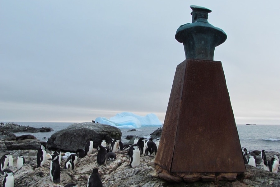 Historic monument and penguins on the Antarctic coast